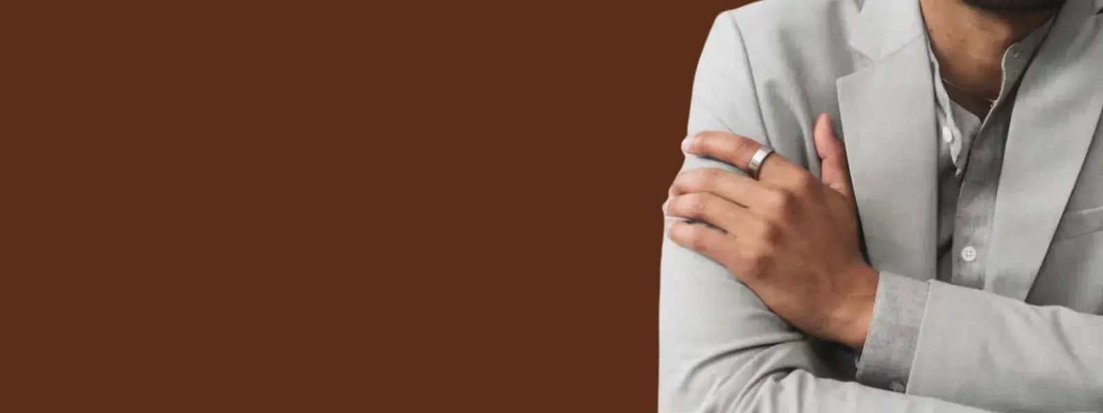 Confident Malaysian man wearing smart ring with beige suit against dark brown background