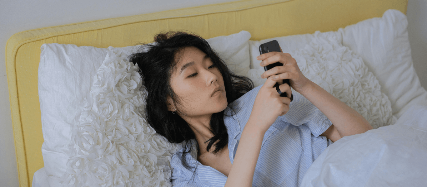 image of a girl scrolling her phone in bed to track her sleep score with jupitercore smart ring